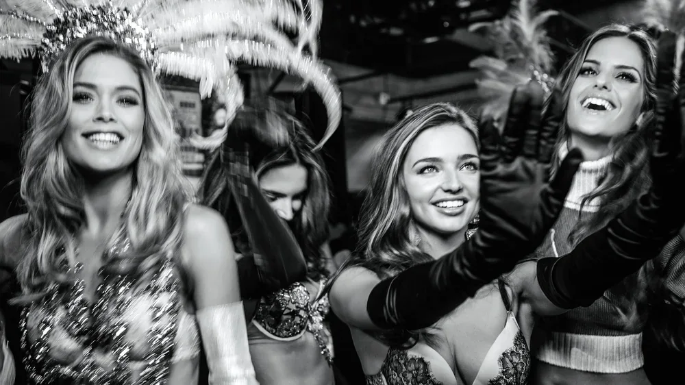 Doutzen Kroes, Miranda Kerr and Izabel Goulart smiling backstage in New York in a black-and-white photograph by Russell James