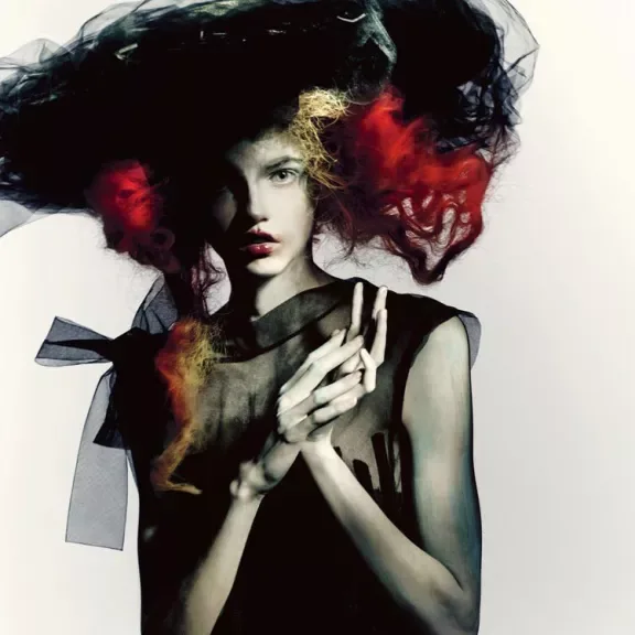 Fashion portrait with pale skin, a dark sculptural hat and red hair, photographed by Paolo Roversi